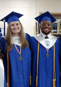 Kacie and DeAndre in high school graduation caps and gowns, smiling at the camera.