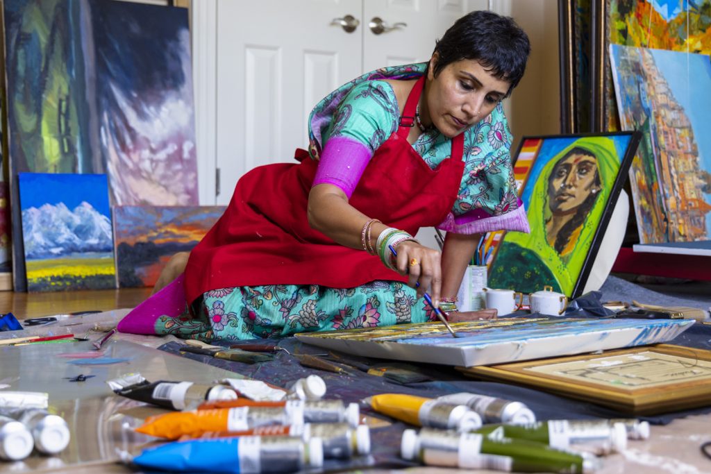 Sreedhari Dari sits on the floor painting.