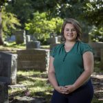 Alison Curry stands outside in a cemetery.