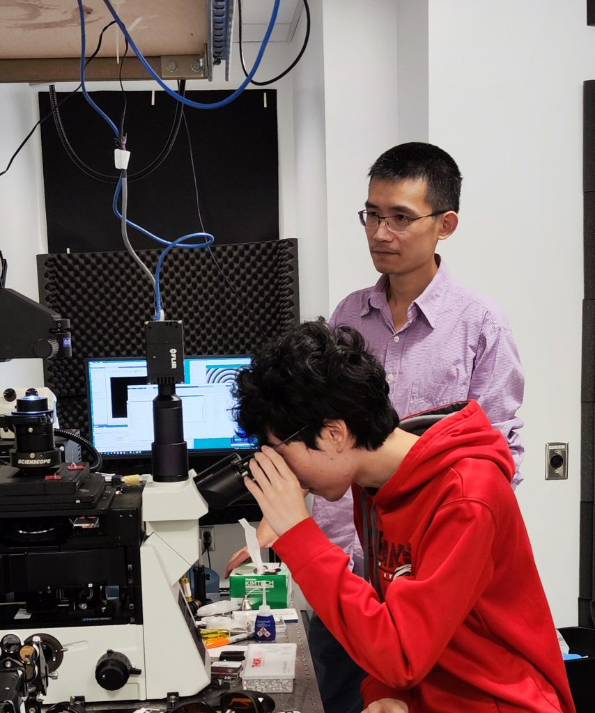 Two researchers look through a microscope in a lab at UNC.