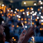 Flickers of candlelight fill the darkness of the Smith Center during a vigil for Zijie Yan.