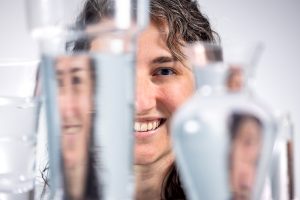 Taylor Teitsworth's face behind two glasses of water, which show distorted reflections of her face.