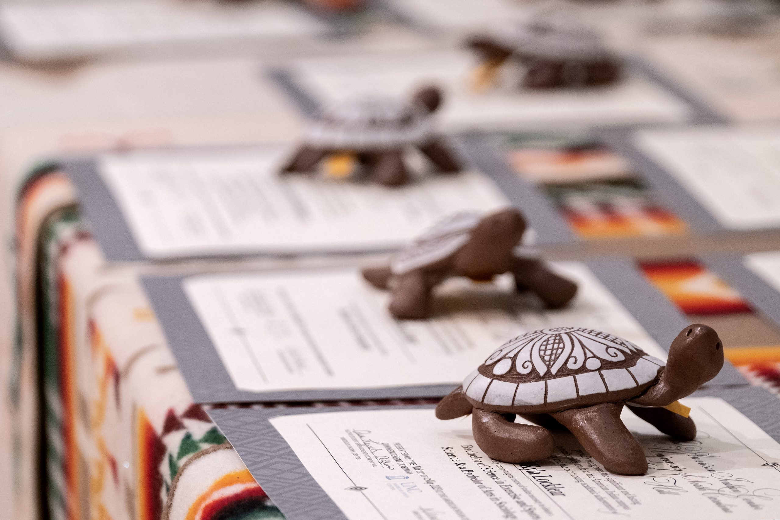 Turtle figurines on paper certificates on table at American Indian Center Commencement Ceremony