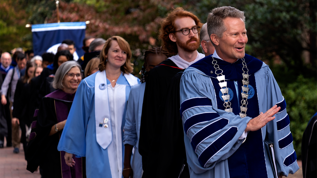 Chancellor Kevin Guskiewicz leads a line of faculty members as they march in the University Day processional outside.