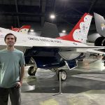 John Migliore stands in an airplane hangar in front of a "United States Air Force" craft.