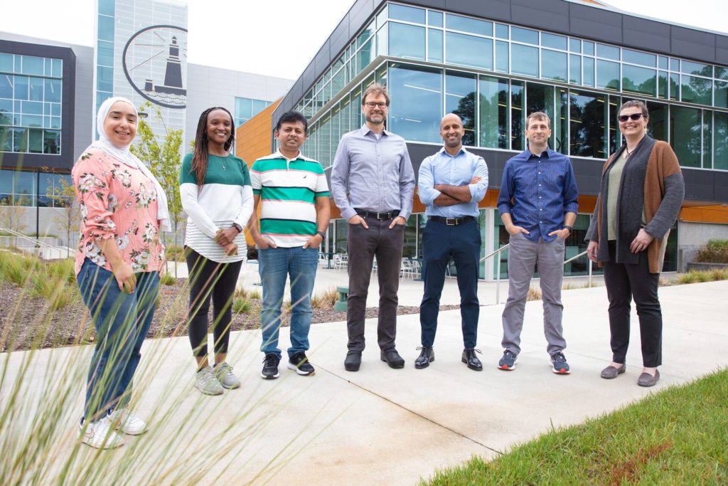 The Triangle Biotechnology Group stands outside in front of their building.