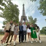 7 study abroad students pose in front of the Eiffel Tower.
