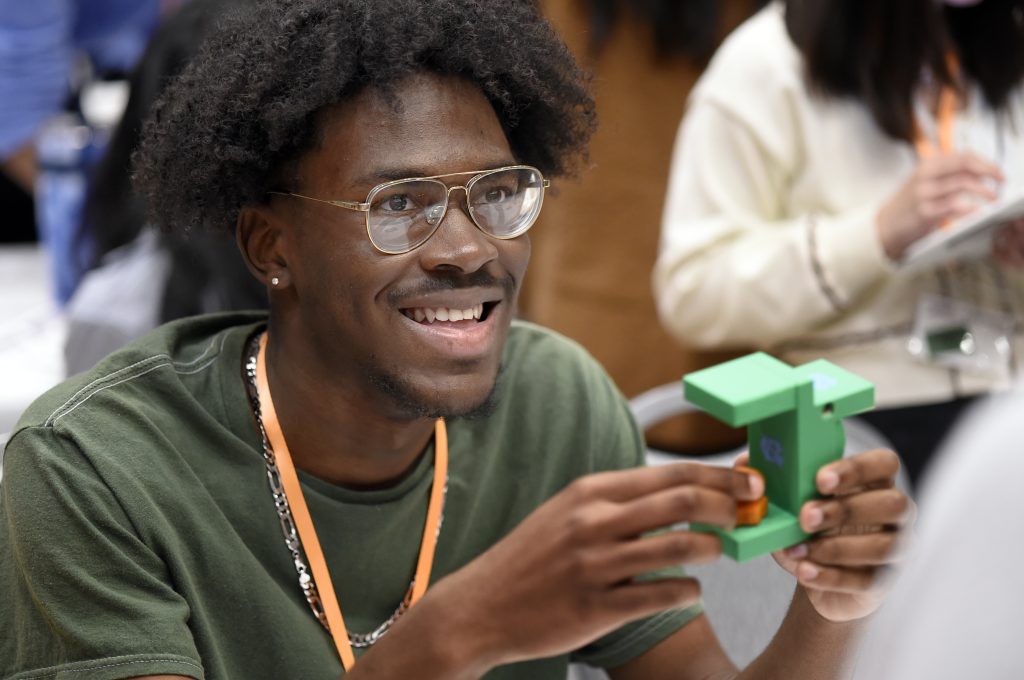 A student shows a small 3D-printed object at MakerFest.