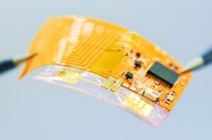 The Spatiotemporal On-Demand Patch, a small strip of yellow rubbery material covered in tiny circuitry. 