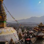 An-aerial-drone-photo-of-Swayambhu-shows-the-main-stupa-and-temple-complex-in-the-foreground-and-Kathmandu-in-the-background.