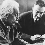 Archive photo of Albert Einstein and Robert Oppenheimer sitting and looking over a notebook together.