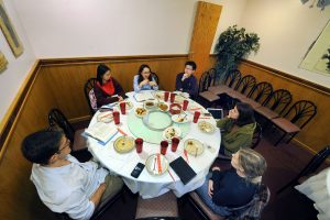 Students sit around a round table discussing a book in 2018 at Gourmet Kingdom.