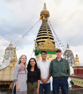 A group photo of the research team in front of the temple smiling at the camera.
