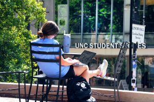A student sitting on a bench studies outside in front of the water fountain near Bynum Hall, (photo by Donn Young)