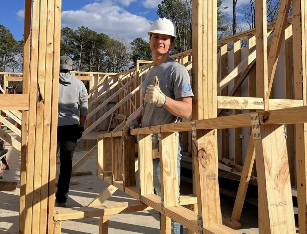 Will Nichols wears a hard hat and gives a thumbs up on construction for a Habitat for Humanity project.
