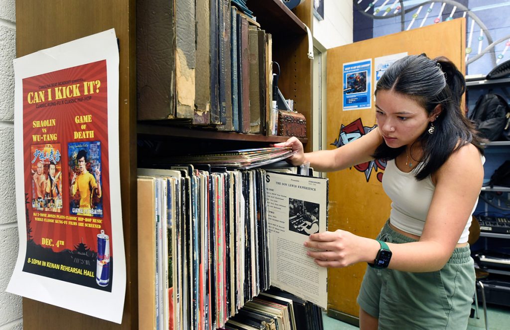A female student rifles through a shelf of vinyl albums in the Beat Lab at the Carolina Hip Hop Institute summer 2024.