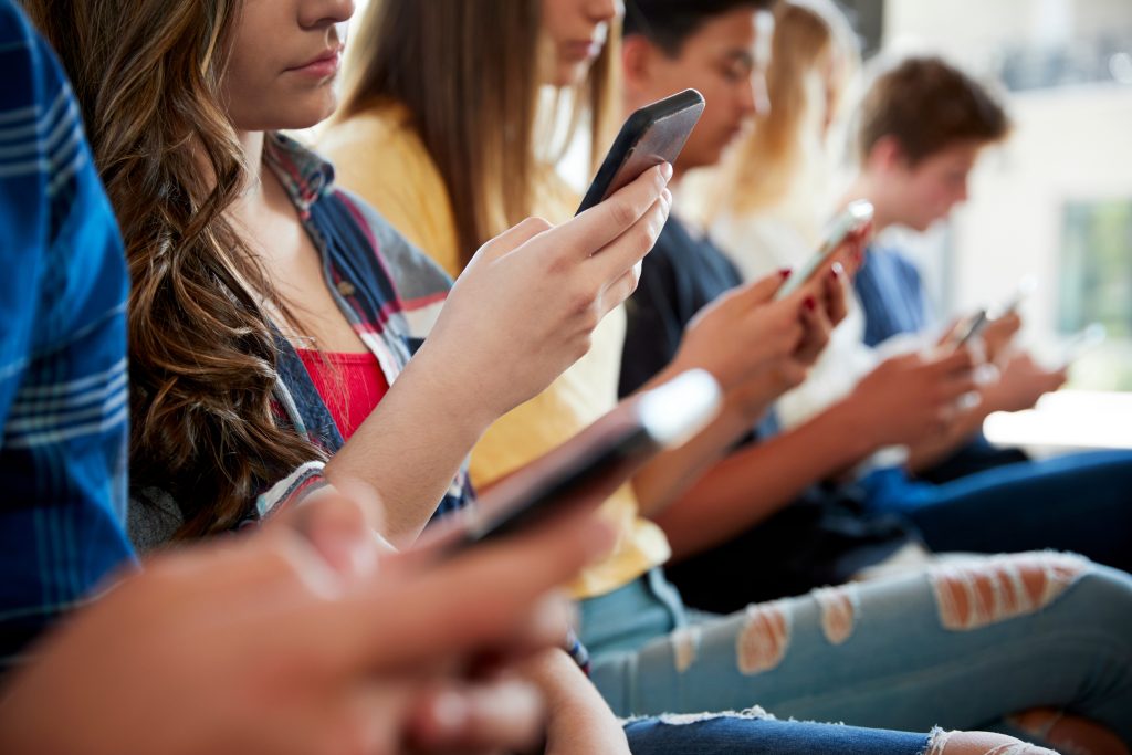 Closeup of teens looking at social media on their mobile phones.